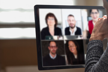 Closeup of man talking with colleagues and discussing work project online. Man participating in an online conference at home, focused on his computer monitor, engaging in a virtual conversation alone