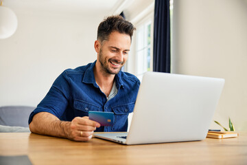 Man paying online with credit card using laptop at home