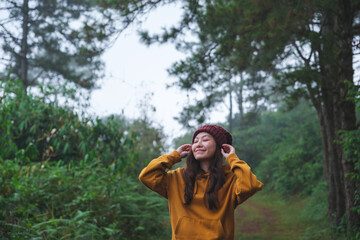 Portrait image of a woman with closed eyes holding hat in the forest