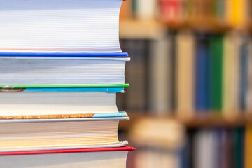 A stack of books on the table on the background of bookshelves