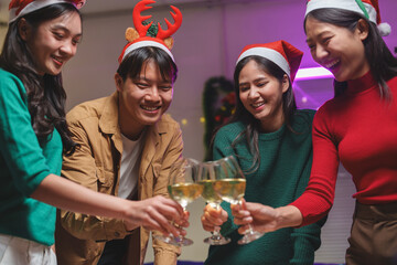 Groups of male and female friends organize parties, happily drinking wine, clinking drinks, eating food and snacks, dancing and singing together. New Year celebration concept.
