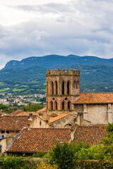 Red brick bell tower of Saint-Lizier Cathedral against the backdrop of the Ariège mountains