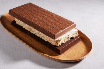A wooden platter with traditional Spanish Christmas sweets: turron in various flavors on a beige stone background