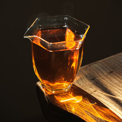 A beautifully artistic glass filled with amber liquid resting on a wooden table surface