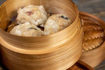 Chinese dim sum dumpling on bamboo wooden basket bowl on wooden table