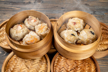 Assorted chinese dim sum dumpling on bamboo wooden basket bowl on wooden table
