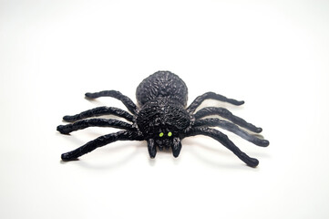 Realistic black spider toy with green eyes isolated on white background. Perfect for Halloween decorations, pranks, or educational purposes