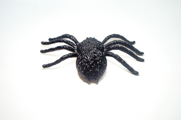 Realistic black spider toy with green eyes isolated on white background. Perfect for Halloween decorations, pranks, or educational purposes