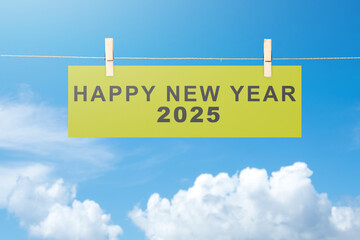 Text of Happy New Year 2025 written on hanging paper with blue sky background © Leo Lintang