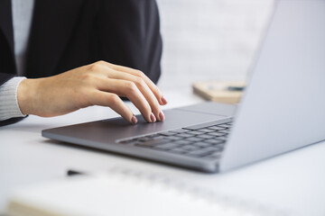The image details a woman's hands typing on an advanced laptop keyboard, with the office surroundings blurred in the background