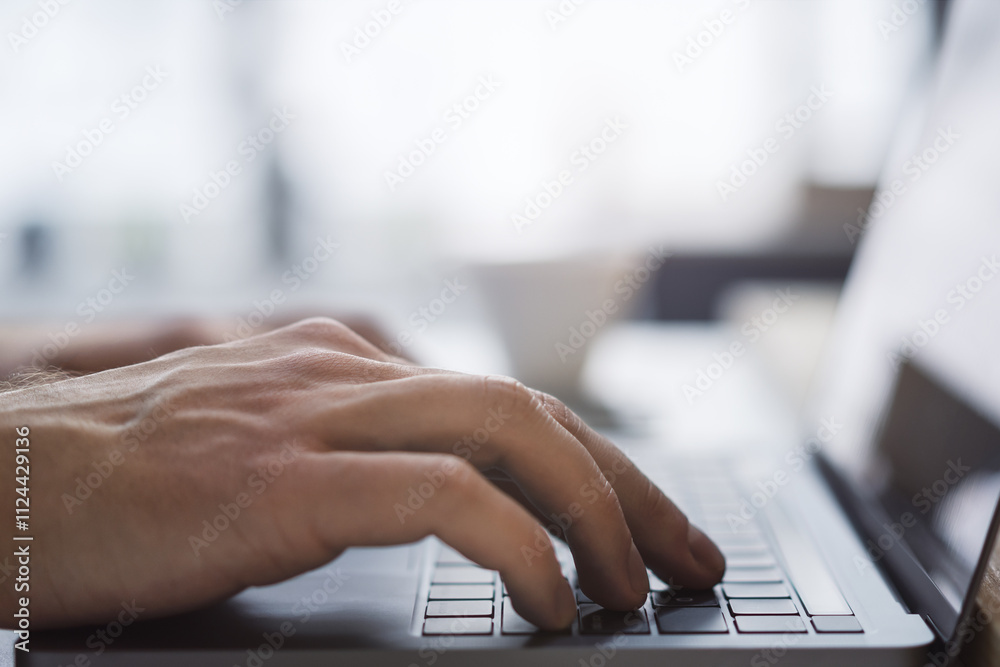 Aufkleber The picture captures a man's hands up close as they type on a sleek laptop keyboard, with an office setting appearing blurred in the background
