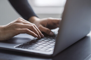 In the blurred setting of an office, a close-up shot captures a woman's hands typing on a modern...