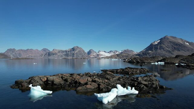 Aerial footage of Greenland's landscape. Untouchable and isolated nature. Icebergs and ice floes floating on the calm waters of the Arctic. Glacier visible in the background. Filmed in Greenland. 