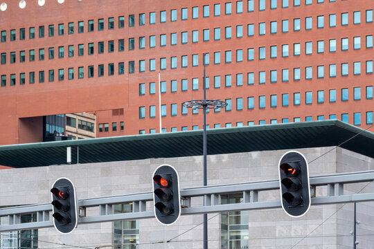 The image captures a row of traffic lights in focus, set against a backdrop of a striking modern architectural building, blending urban elements and signage.