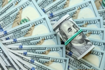 Roll of hundred dollar bills USD banknotes lies on big amount of united states money