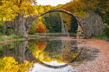 Rakotz Bridge, Rakotzbrücke or Devil's Bridge in Kromlau, Saxony, Germany. Colorful autumnal landscape with reflection in water in form of a full circle. Fairytale place