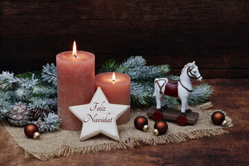 Tarjeta navideña Feliz Navidad: Caballito delante de velas marrones y ramas de abeto con el texto...