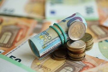 Roll of euro currency money bills and many euro cents on banknotes of european union