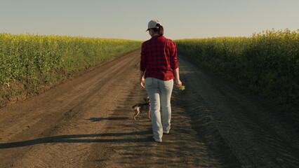 Fototapeta premium Woman Farmer In Cap Walks In Field. Agriculture. Young Green Rapeseed Harvest. Agronomist Control And Manages Farming. Business Woman Working On Farm.