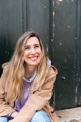 Vertical portrait of a woman in front of a green gate in the street