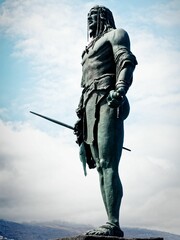 Low-angle shot of a sculpture of an indigenous Guanche warrior with his spear and tribal clothing.
