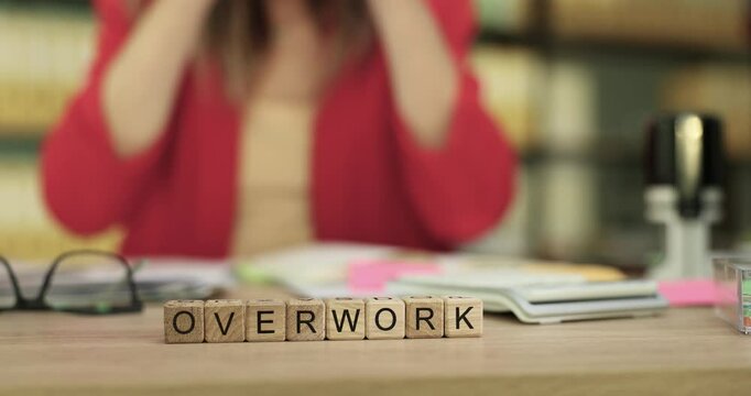 A visual representation showcasing overwork, depicted through scrabble letters and a bustling workspace environment