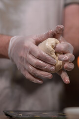 Hands in gloves kneading dough for baking