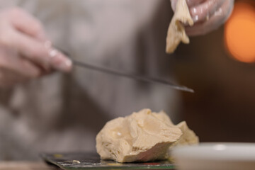 Hands in gloves kneading dough for baking