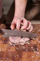 Male hands cutting cooked meat beef on a wooden board