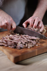 Male hands cutting cooked meat beef on a wooden board