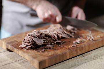 Male hands cutting cooked meat beef on a wooden board