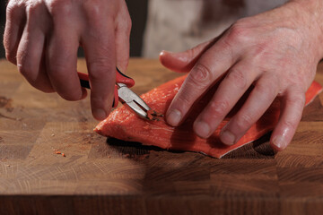 Male hands removing bones from red fish