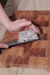 Male hands cutting raw shrimp on wooden board