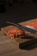 Male hands cutting red salmon fish on a wooden board