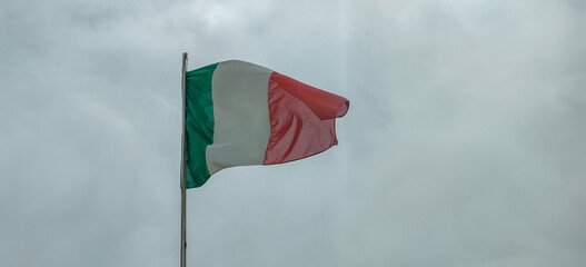 A green, white, and red flag is brightly waving in the gentle wind