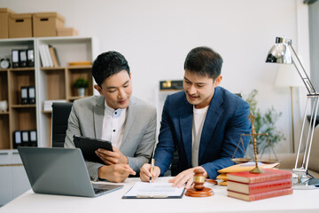 Fototapeta premium Asian business team and lawyers discussing contract papers sitting at the table. Concepts of law