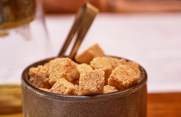 Brown cane sugar in a cup on a wooden table. Selective focus.    