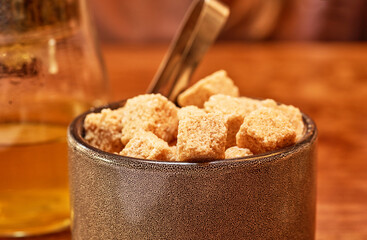 Brown cane sugar in a cup on a wooden table. Selective focus.    