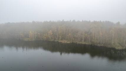A peaceful and serene view of a tranquil lake, beautifully surrounded by colorful autumn foliage and soft mist