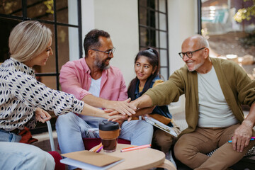 People at community meeting stacking hands to symbolize unity