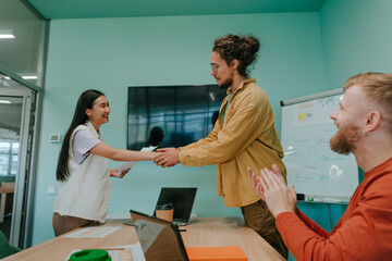 Happy businessmen congratulating businesswoman at office
