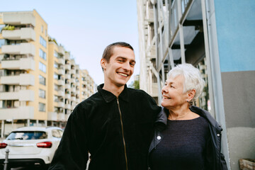 Mid adult man and senior woman smiling outdoors in urban area