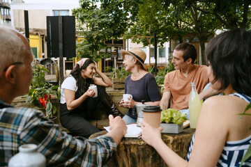 Group of people enjoying conversation and drinks in an urban garden setting.