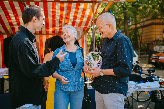 People conversing and smiling at a flea market outdoors.
