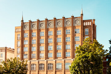 Neo-gothic red brick building in Hansa city, Rostock, Germany with clocks and symmetrical windows.
