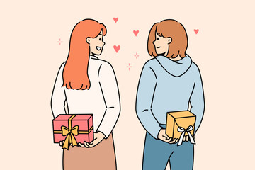 Positive girls hold gifts boxes behind their backs and look at each other lovingly, showing sympathy and affection. Young casual women exchange gifts on eve of march 8 or valentine day.