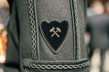 Detailaufnahme einer traditionellen Trachtenhose mit einem herzförmigen Emblem, das zwei gekreuzte...
