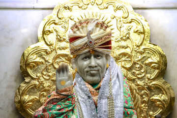 Statue of Sai Baba with Ornate Golden Background and Colorful Attire