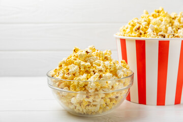 Popcorn box. Red and white striped buckets of salted popcorn on a colored background. Cinema and entertainment concept. Movie night with popcorn. Delicious appetizer, snack. Place for text.