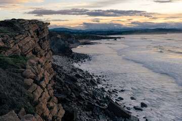Summer sunset from the cliff at the atlantic coast of Spain with snowy mountains on the background